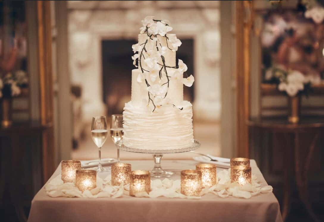 Elegant white crystal frilled wedding cake decorated with lifelike sugar orchids, showcasing intricate fondant layers and shimmering edible crystals, created by Tuscan Wedding Cakes.